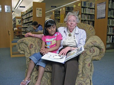 Janet Dempsey, a beloved teacher of both Carol Morton and Gen. David Petraeus as well as a long-time Friend of Cornwall Library, is pictured reading to Aneeka Phodnis, a young library patron, while seated in one of the four new chairs donated in memory of Sixtus Petraeus.