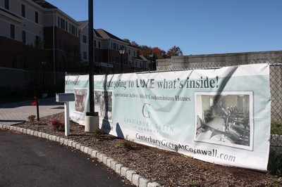 The banners promoting the condominium units at Canterbury Green still line the driveway.