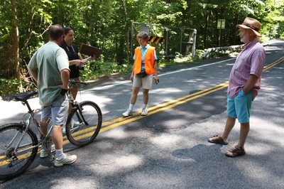 Trustee Barbara Gosda gets the emails of two bikers before the enter the closed section of Route 218 as former mayor Joe Gross looks on.