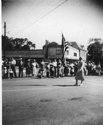Winnie Swenson, a popular businesswoman who ran an insurance company, carries the flag in a parade through the village square.