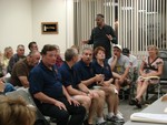Village officers in the front row listened to Pat Welch, one of several village residents who spoke at the meeting.