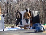 Workers pick up the strewn trash from the dumpster that was knocked over by vandals.