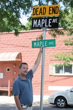 DPW superintendent Dave Halvorsen compares the old green sign to the larger, new black sign on Maple Avenue.