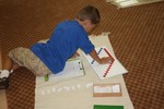 This boy worked on math problems by himself on a floor mat.