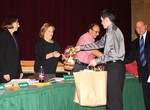 Student representative Anthony Zanin hands a gift basket to board member Melanie Mulroy-Robinson.