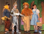 The scarecrow, the tin man and the lion follow the yellow brick road with Dorothy.
