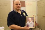 Officer Lug with a photo of Officer D'Egidio that is kept inside the village police station.