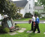 Veterans Bill Fulton and Tom Quinlan lay a wreath at a memorial near the village elementary school.