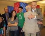 Mayor Coyne hugs Trustee Kane while newly-elected trustee Peter Russell (far left) and his family look on.