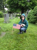 Cub Scout Kevin Hughes places a flag at St. Thomas Cemetery.